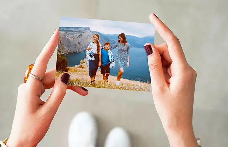 Hände halten einen Fotodruck von drei Kindern im Urlaub