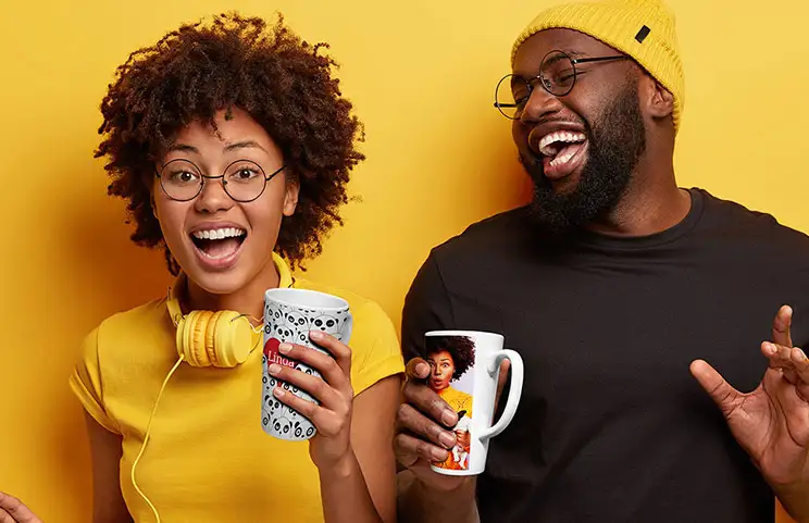 Junges Paar hält personalisierte Latte-Tassen mit Text und Bildern
