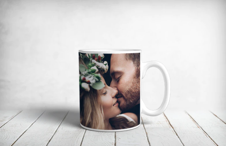 ["Personalised Photo Mugs by Printerpix", "Mother and baby holding a Printerpix mug with cartoon design and 'Dad' text", "Personalised photo mug with image of a crawling baby in an animal onesie", "Mother and daughter holding custom-designed photo mugs with family photos", "Kissing couple with personalised mugs with text on them", "Personalised photo mug with own photo of a dog on it", "", "", "", ""]||||||||||